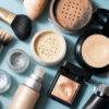 Puderdöschen und Make-Up-Flaschen deutscher Kosmetik Hersteller auf türkisfarbenem Untergrund