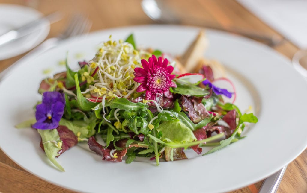 A greendish decorated with flowers, herbs and salad