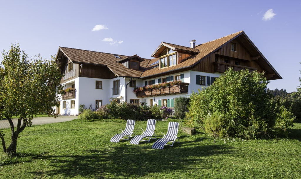 Three loungers on a meadow in front of a fancy holiday home in Bavaria.