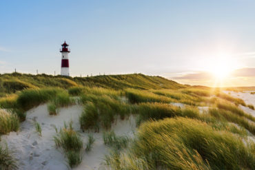 Lighthouse on Sylt, one of the most famous islands in Germany, in front of green dunes in the evening sun