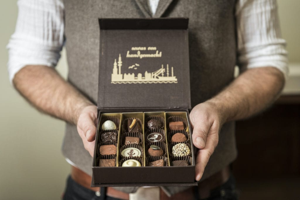 Ein Mann hält eine Schachtel Pralinen mit einer Auswahl an verschiedenen Sorten
