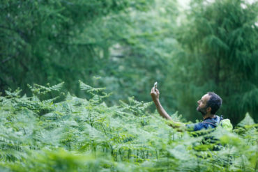 Mann im Wald auf der Suche nach einem Signal fürs Geocaching in Deutschland