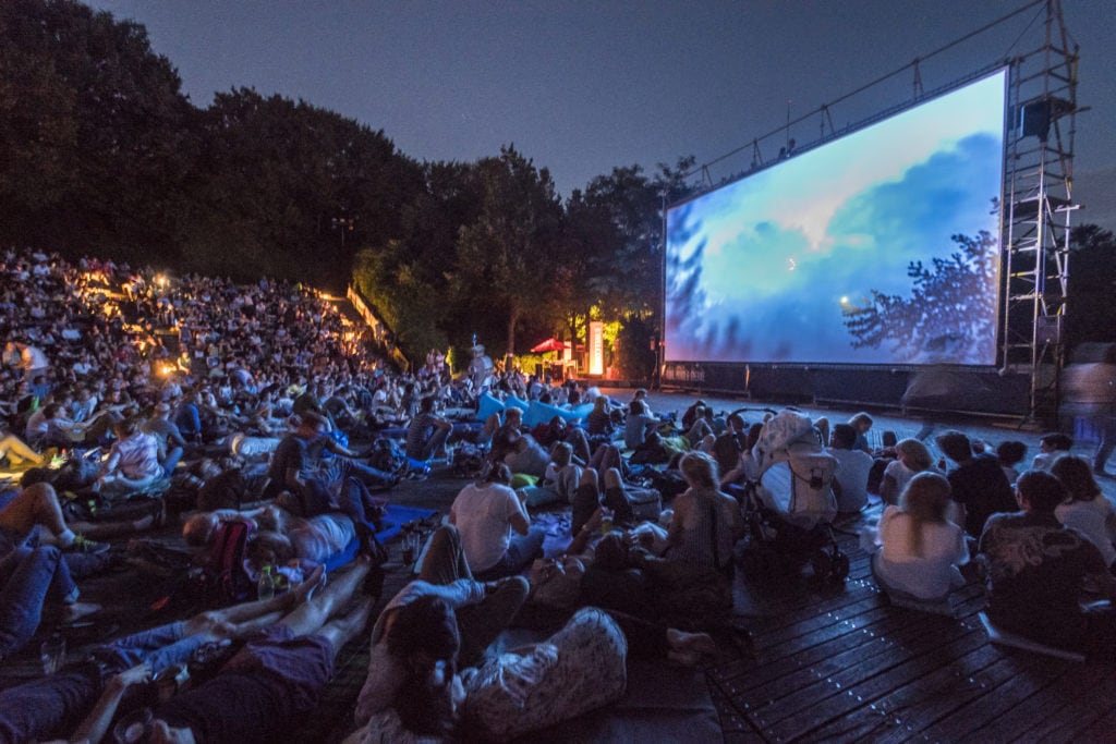 Open-air cinema plays in the background and you can see the many people who watch the spectacle with enthusiasm. One of the special places in Munich.