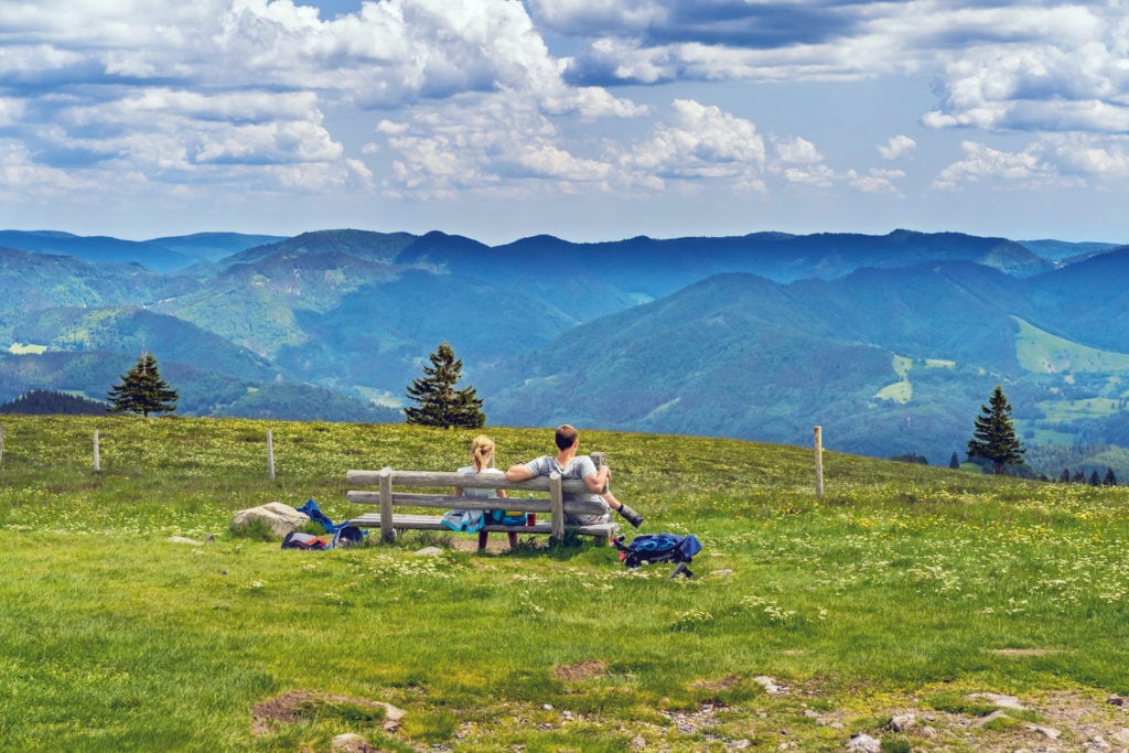 Pärchen sitzt auf einer Parkbank und genießt die Aussicht auf den Schwarzwald