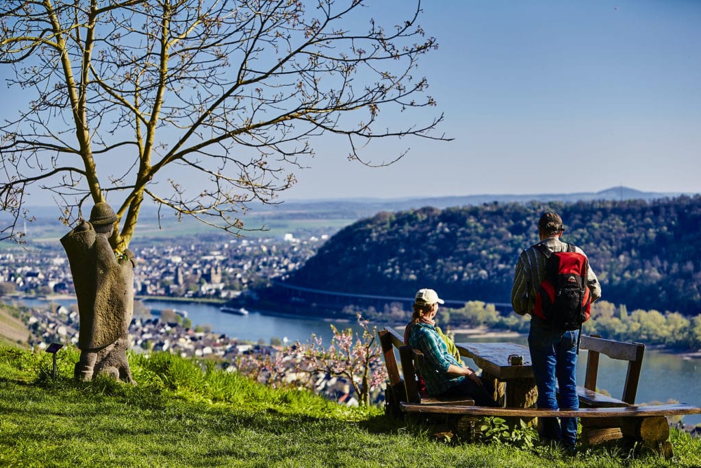 Zwei Wanderer sitzen an Aussichtspunkt und schauen über Bad Hönningen