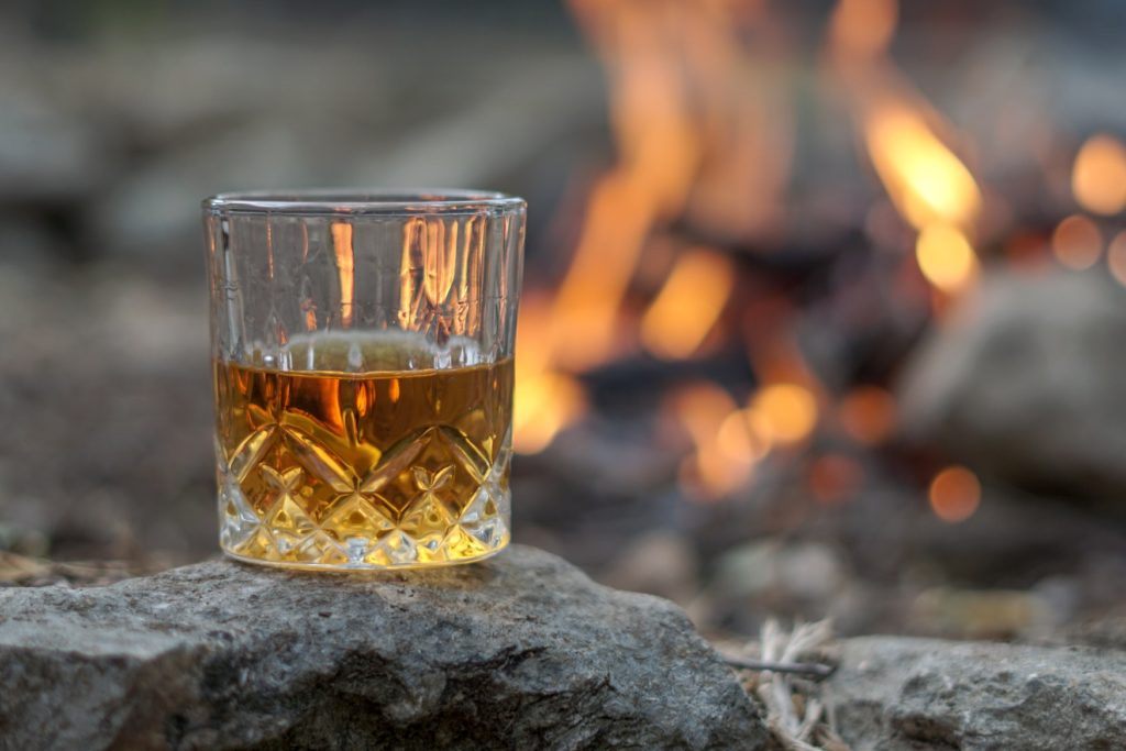 Whiskey in einem Glas direkt an einem Feuerplatz