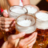 Menschen die mit einem Bierkrug anstoßen in Biergarten in Augsburg