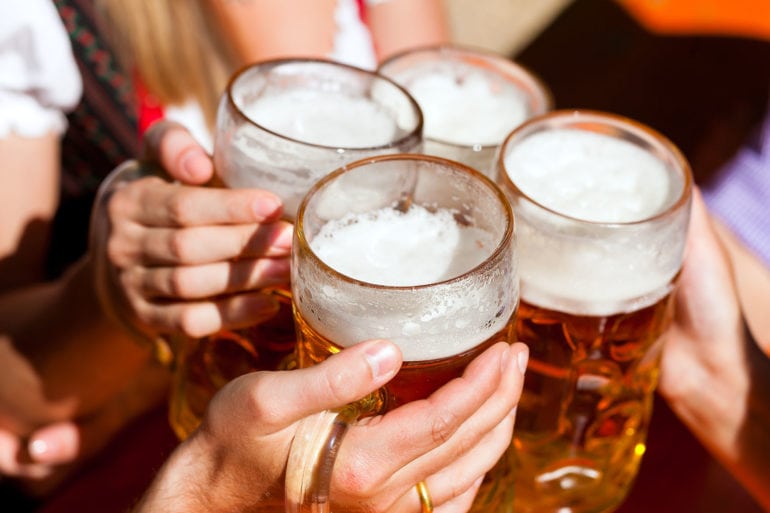 Menschen die mit einem Bierkrug anstoßen in Biergarten in Augsburg
