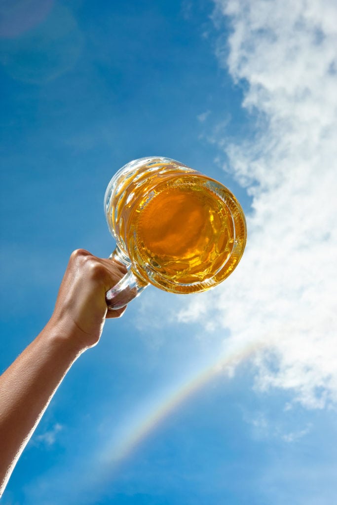 A beer glass is held up to the sky