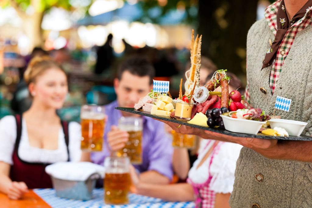 A man serves a tray with a Bavarian snack.