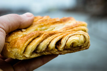A man is holding a Franzbroetchen, a typical pastry of Hamburg