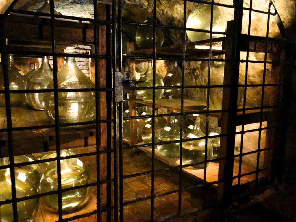bulbous bottles wait in the shelves of the rock cellar