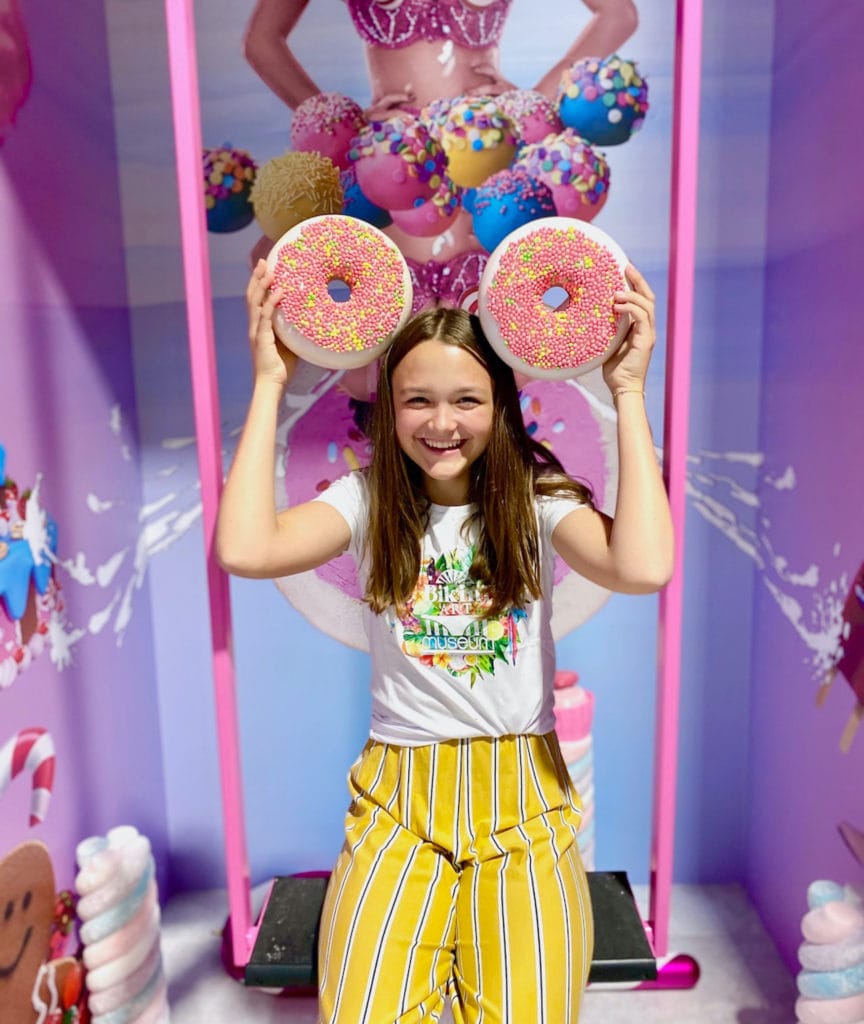 Mädchen posiert mit zwei Kunststoff-Donuts auf Schaukel 