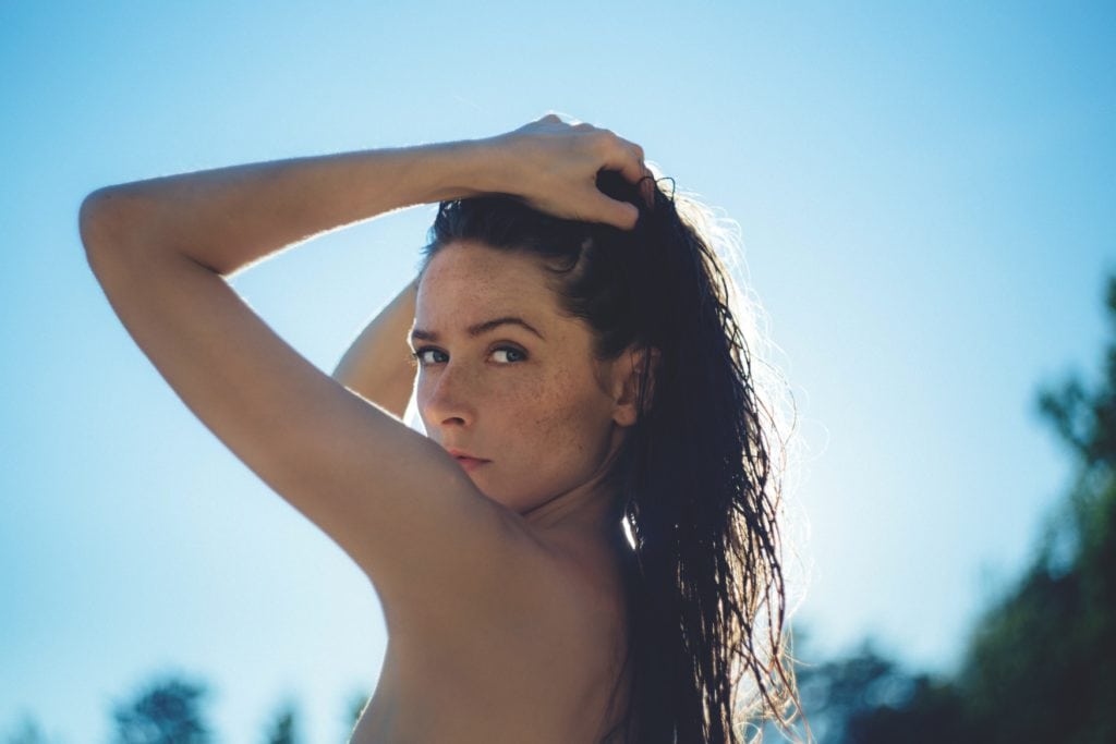 Frau posiert mit nacktem Oberkörper vor der Kamera an FKK-Strand in Deutschland