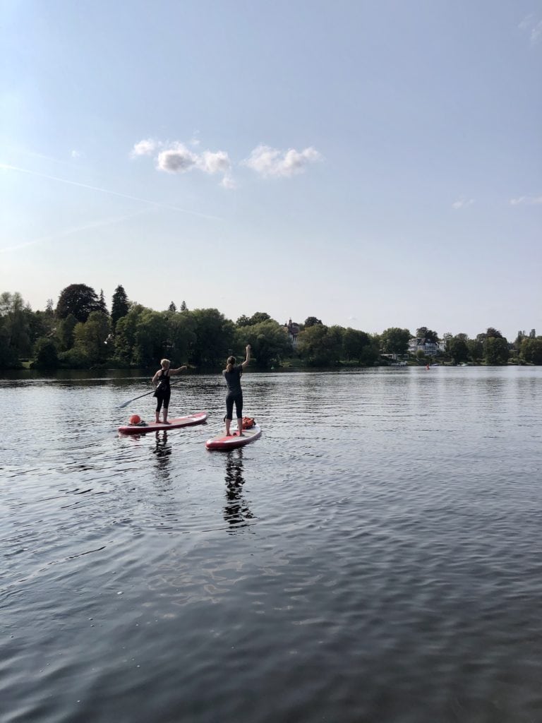Two women on SUPs paddle across the idyllic lake Griebnitzsee, Brandenburg