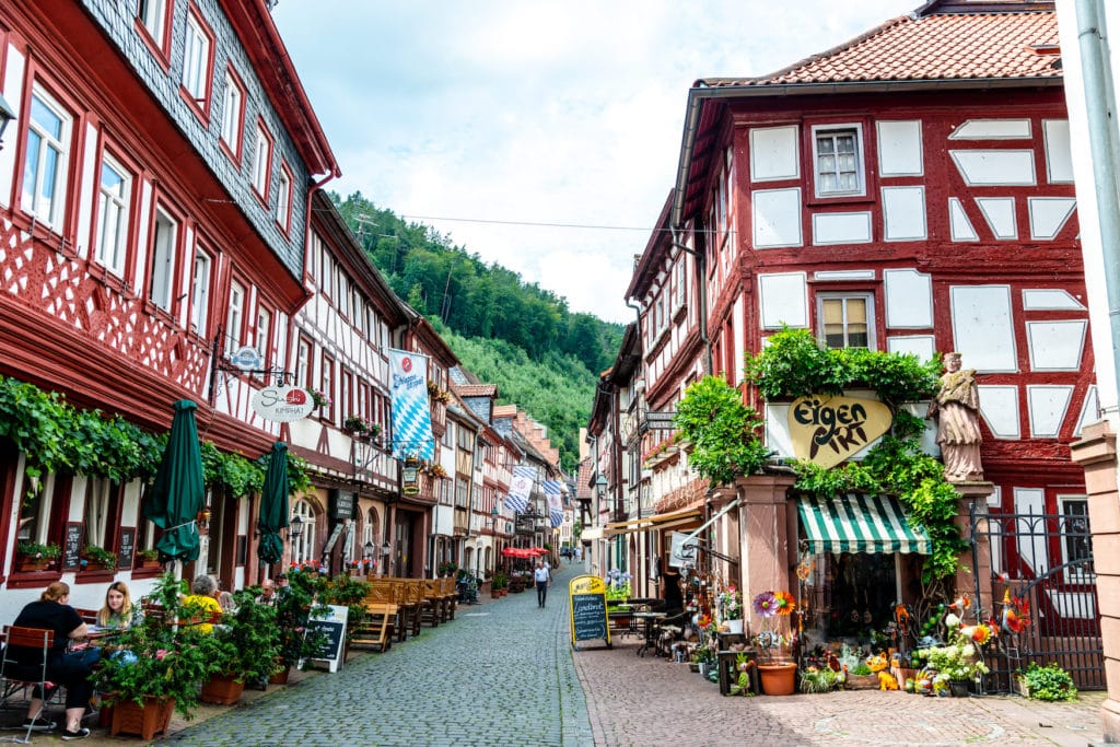 Street with colorful half-timbered houses, peaple, restaurants, shops nearby marketplace in old german town Miltenberg am Main river
