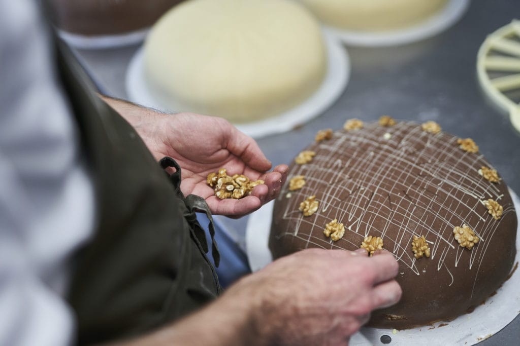 Konditor verziert Schokoladen-Torte mit Walnüssen