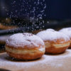 Icing sugar trickles onto doughnuts