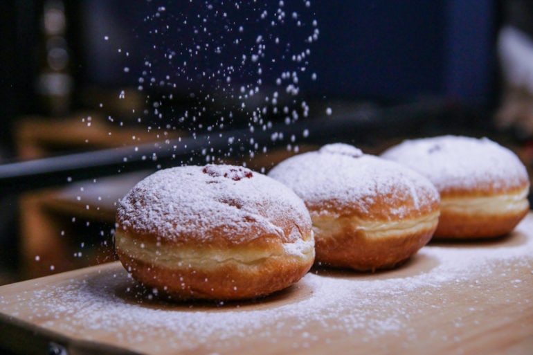 Icing sugar trickles onto doughnuts