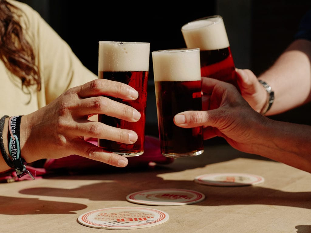 Menschen stoßen mit Alt, eine Biersorte aus NRW, an