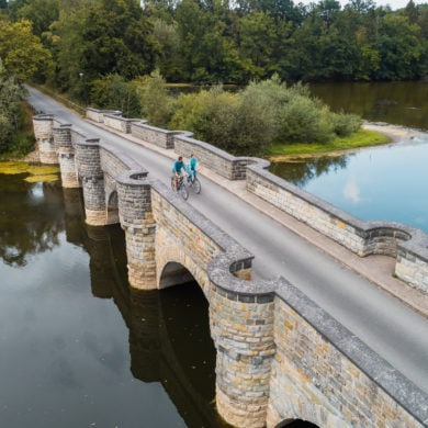 Woman and man cycling over bridge in Sauerland region, Western Germany