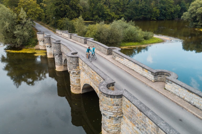 Woman and man cycling over bridge in Sauerland region, Western Germany