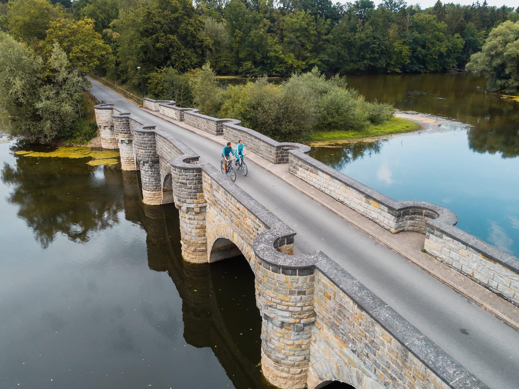Woman and man cycling over bridge in Sauerland region, Western Germany