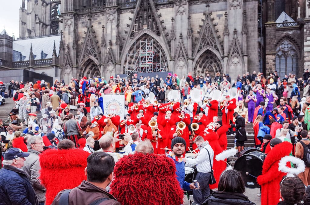 Menschen stehen vorm Kölner Dom und feiern Karneval