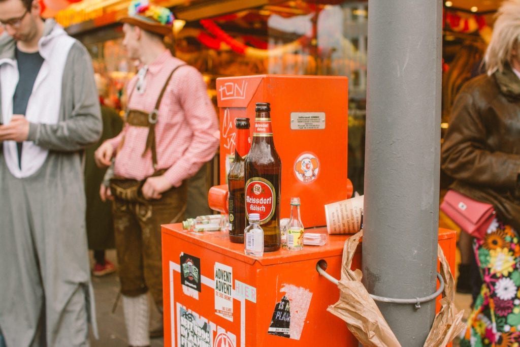Kölschflaschen stehen auf Zeitungsautomat in Kölner Südstadt während Karneval