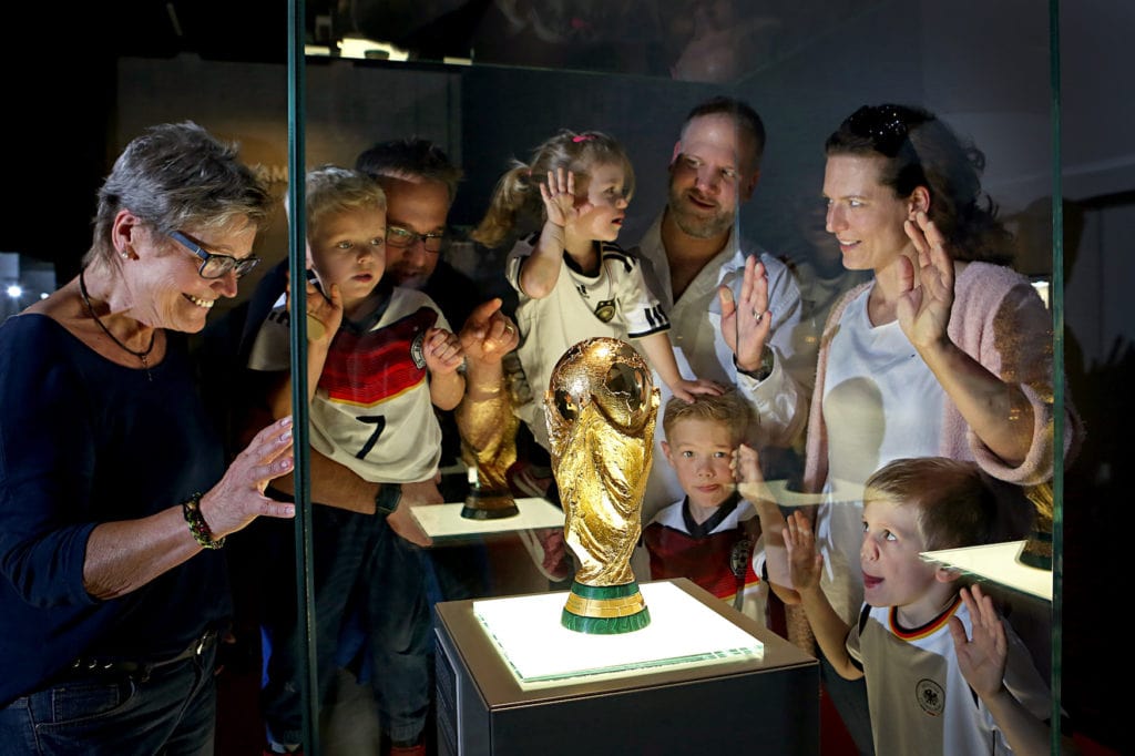Museum visitors stand by display case and look at World Cup winner's trophy