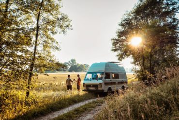 Camper steht in deutscher Natur bei Sonnenuntergang