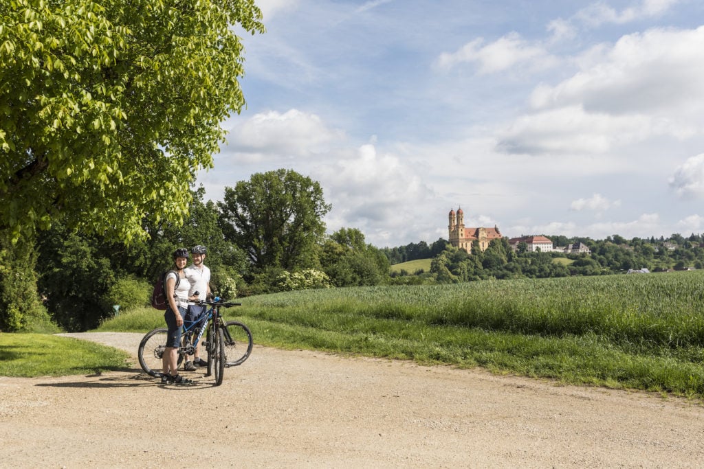 Fahrradfahrer auf dem Kocher-Jagst-Radweg mit der Schönenbergkirche im Hintergrund