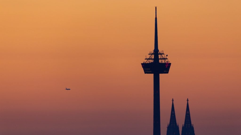 Spitzen des Kölner Doms und des Colonials-Turms vor orangenem Sonnenuntergang