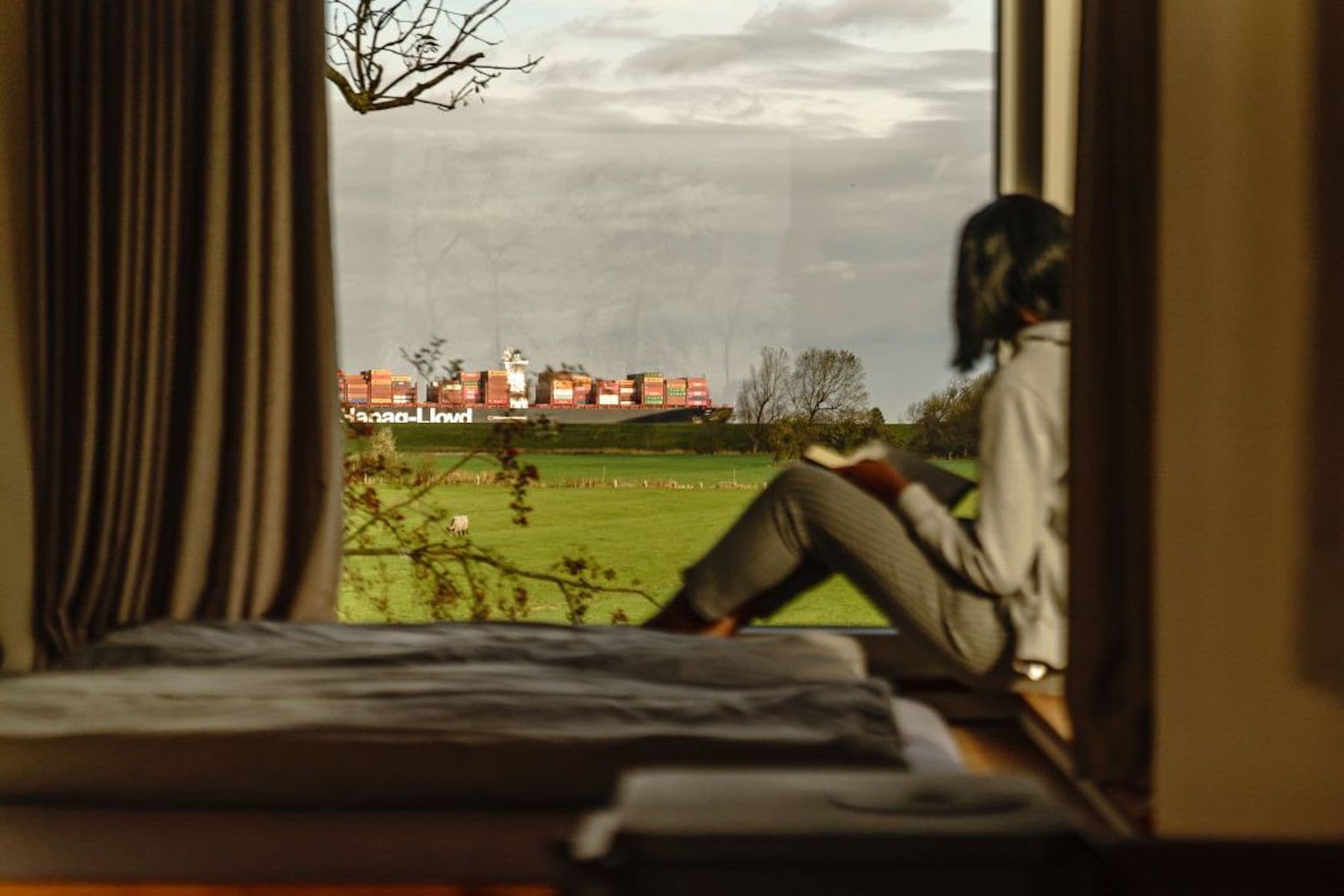 Frau sitzt auf Fensterbank und schaut auf Damm in Otterndorf
