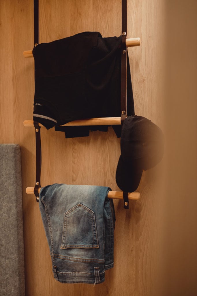 Trousers and cap hanging on coat hooks in hotel room