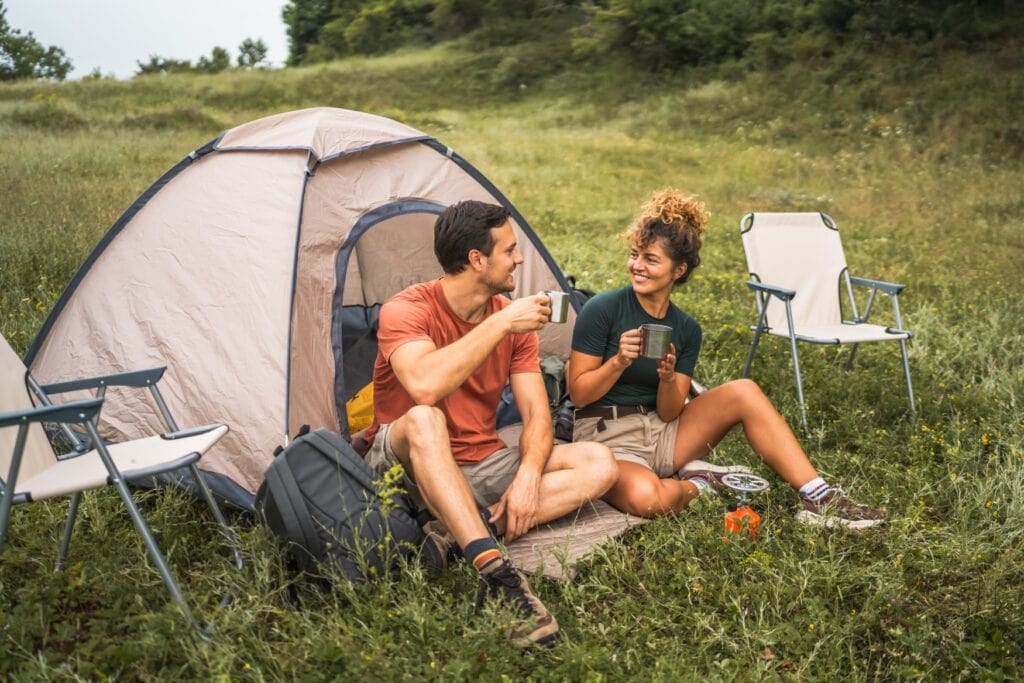 Ein Mann und eine Frau sitzen vor einem Zelt und trinken Kaffee