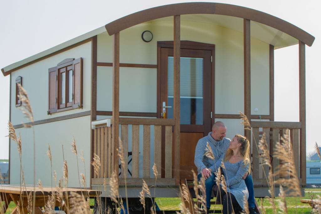 Couple sitting in front of glamping car at the North Sea