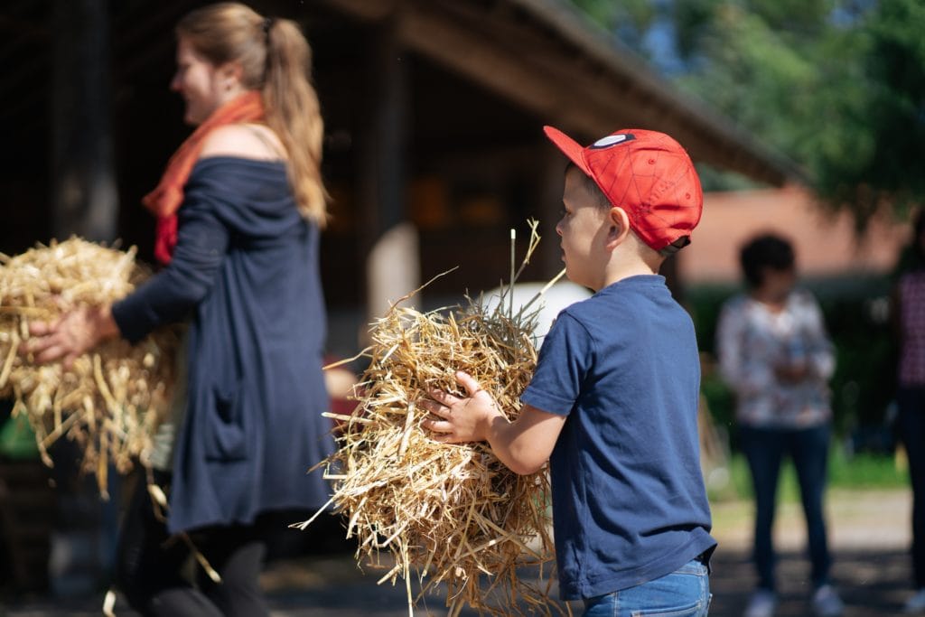 Junge trägt Stroh auf einem Bauernhof