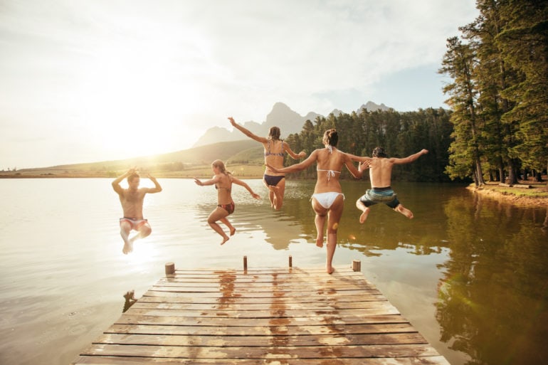 Freundesgruppe springt bei gutem Wetter in den See