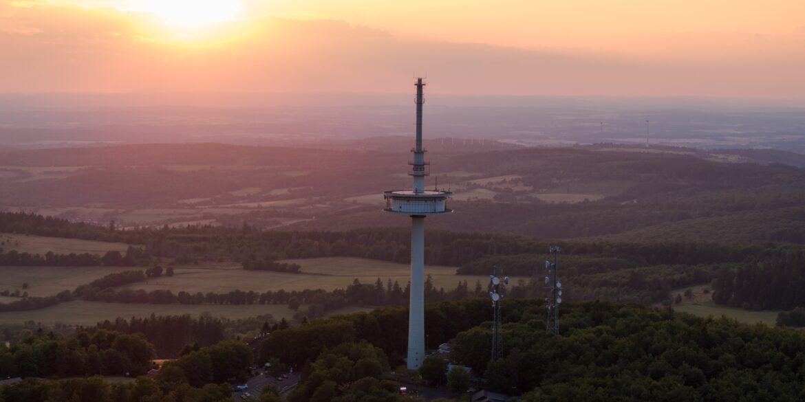 Drohnenaufnahme des Funkturms auf dem Vogelsberg in Hessen, im Hintergrund geht die Sonne unter