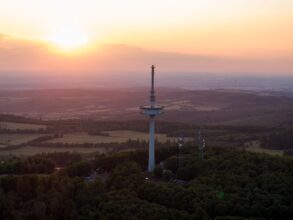 Drohnenaufnahme des Funkturms auf dem Vogelsberg in Hessen, im Hintergrund geht die Sonne unter