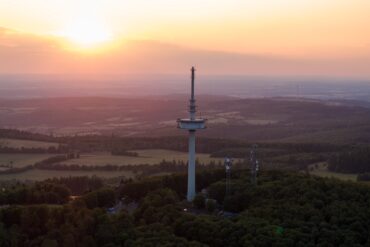 Drohnenaufnahme des Funkturms auf dem Vogelsberg in Hessen, im Hintergrund geht die Sonne unter