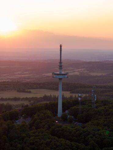 Drohnenaufnahme des Funkturms auf dem Vogelsberg in Hessen, im Hintergrund geht die Sonne unter