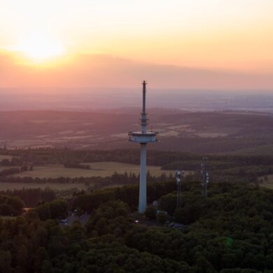 Drohnenaufnahme des Funkturms auf dem Vogelsberg in Hessen, im Hintergrund geht die Sonne unter