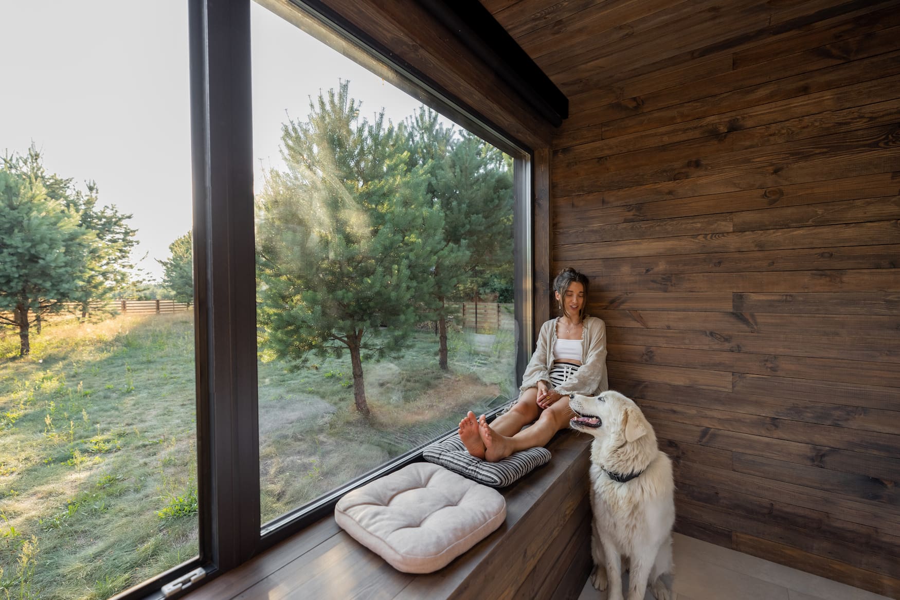 Junge Frau sitzt mit ihrem Hund in einem Landhaus
