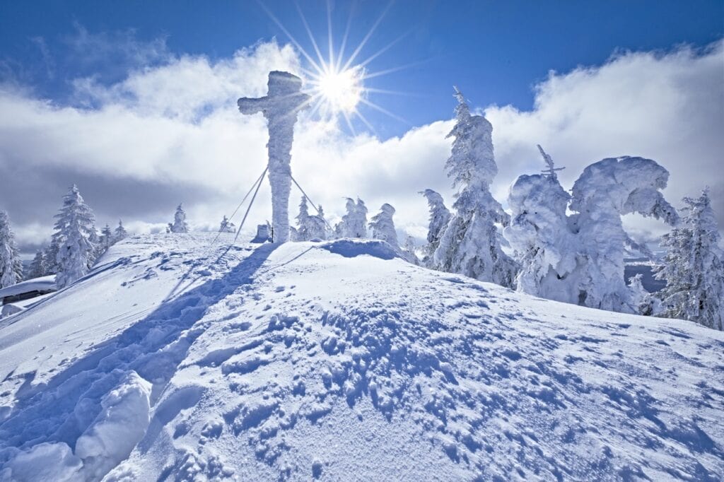 Verschneites Gipfelkreuz auf dem Rachelgipfel, das man während eines Winterurlaub im Bayerischen Wald besuchen sollte