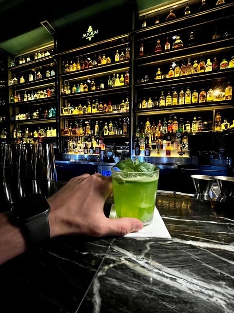 Mann hält grünen Cocktail in die Kamera