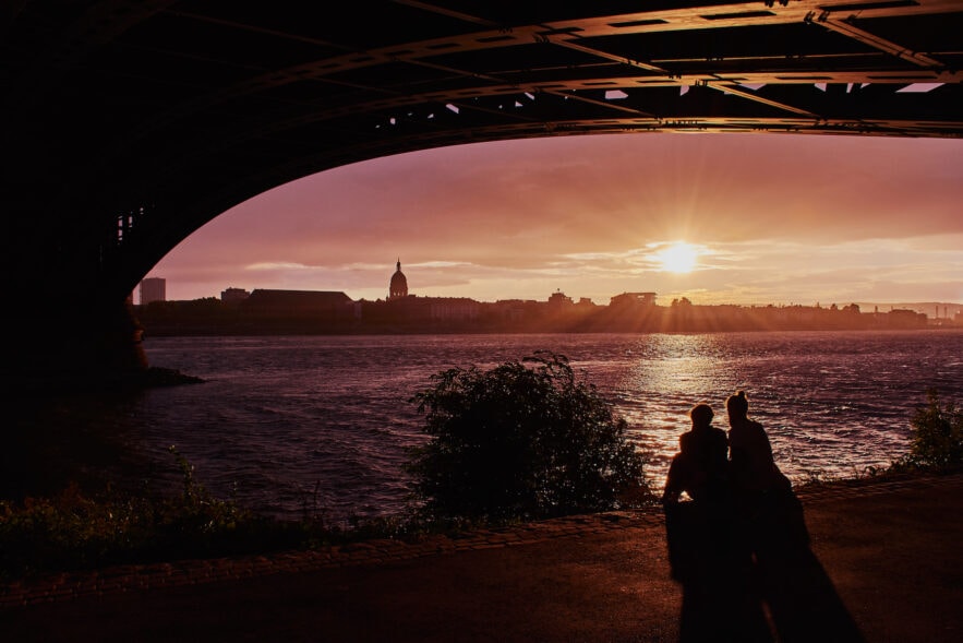 Pärchen sitzt während Sonnenuntergang am Flussufer in Mainz