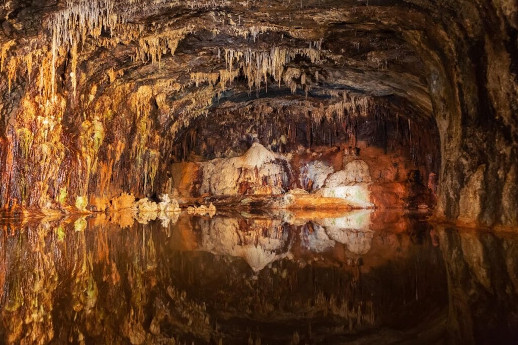 Stalagmites and stalactites reflecting in the water in the colorful Fairy Grottoes in Saalfeld