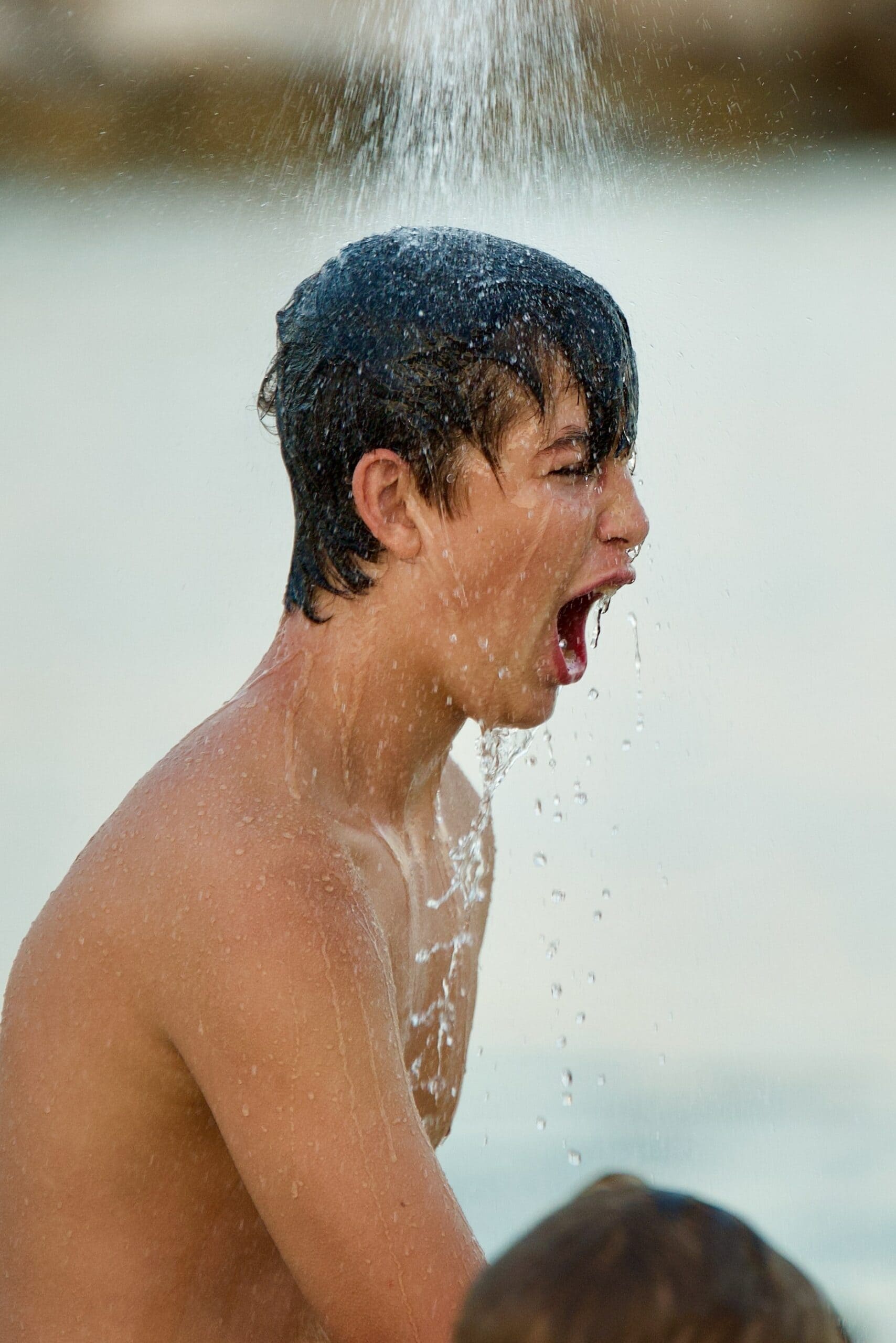 Tipps gegen Hitze: Wechseldusche oder lauwarme Dusche, so wie der Junge auf dem Foto